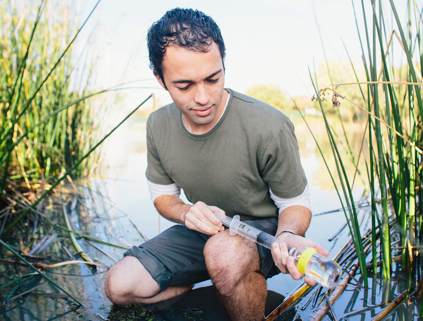 Research student in water collecting samples